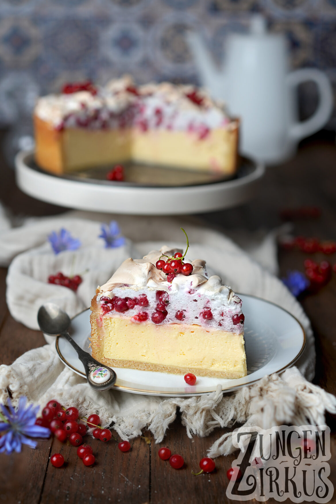 Ein Stück Käsekuchen mit einer Schicht Johannisbeerbaiser oben drauf.