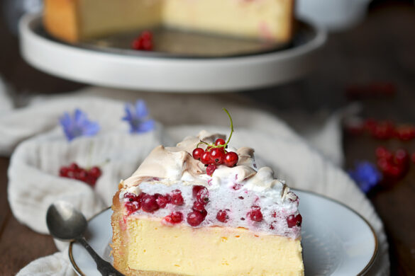 Ein Stück Käsekuchen mit einer Schicht Johannisbeerbaiser oben drauf.