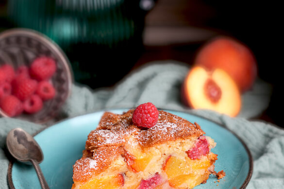 Pfirsich-Melba-Kuchen Ein Stück Rührkuchen mit viel Pfirsichstücke und Himbeeren drinnen.