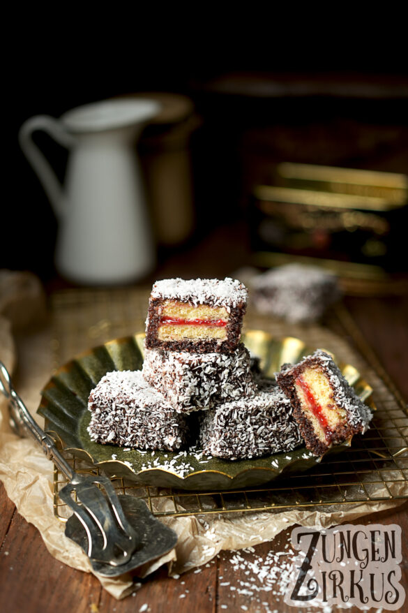 Lamingtons Kuchenwürfel gefüllt mit Konfitüre, in Schokoglasur getaucht und in Kokosflocken gewälzt