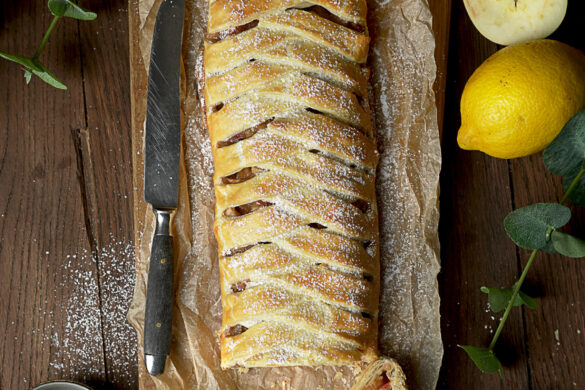 Apfelstrudel auf Backpapier. Strudel mit geflochtener Optik des Blätterteiges