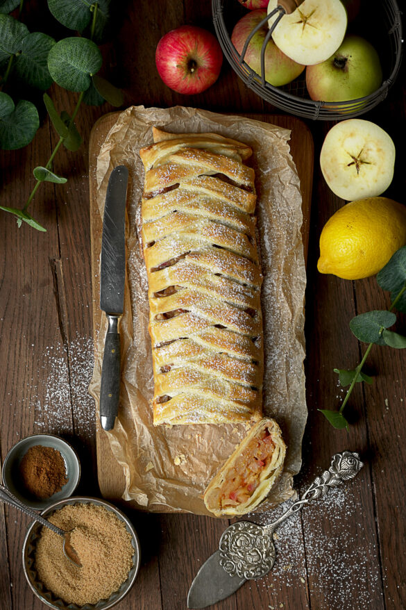 Apfelstrudel auf Backpapier. Strudel mit geflochtener Optik des Blätterteiges